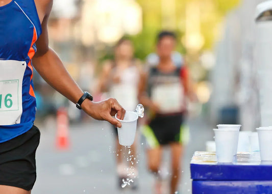 A marathon runner picking up a cup of water during a race